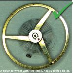 A balance wheel with two small, neatly drilled holes.