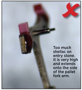 Too much shellac on entry stone. It is very high and extends onto the side of the pallet fork arm.